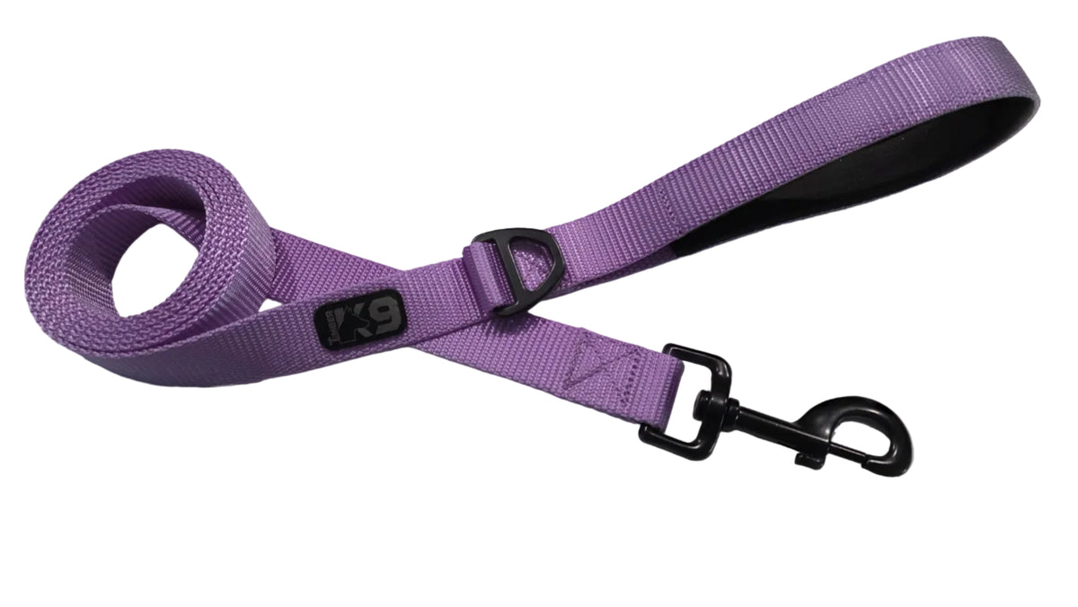 A purple woven dog leash with black hardware, including a snap hook clasp and a black comfort handle grip, laid out on a white surface.
